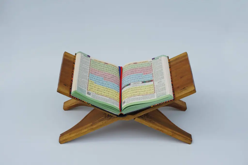 An open Quran displayed on a wooden stand, symbolizing Islamic faith and spirituality.