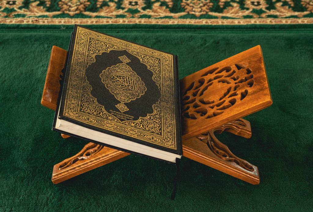 A Quran displayed on an ornate wooden rehal in a mosque setting, symbolizing spirituality.