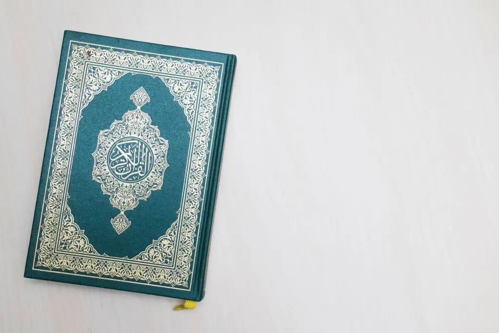 A Quran with intricate Arabic design placed on a white surface, highlighting its spiritual essence.