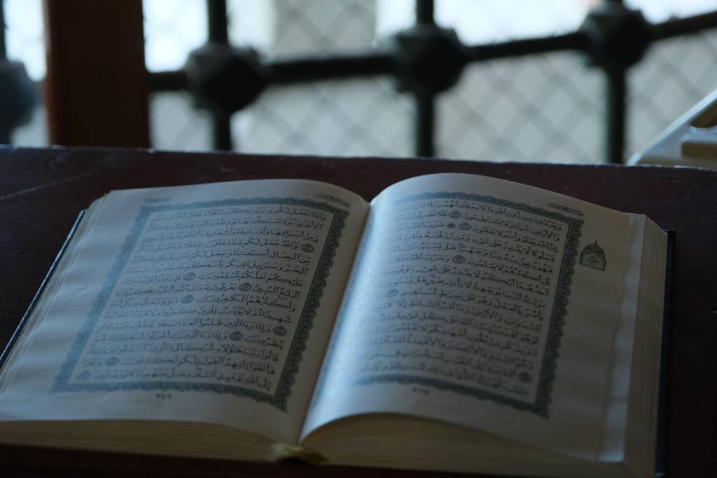 A Quran set on a wooden lectern with soft lighting creating a serene ambiance.