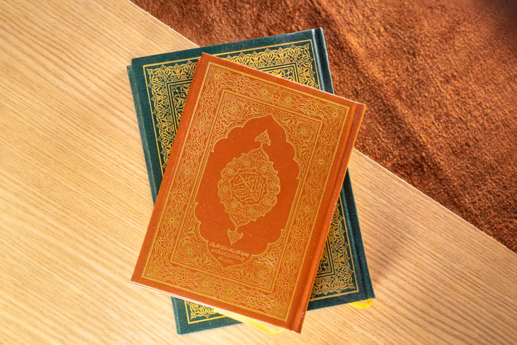 Top view of two Quran books with ornate covers placed on a wooden table, symbolizing peace and spirituality.