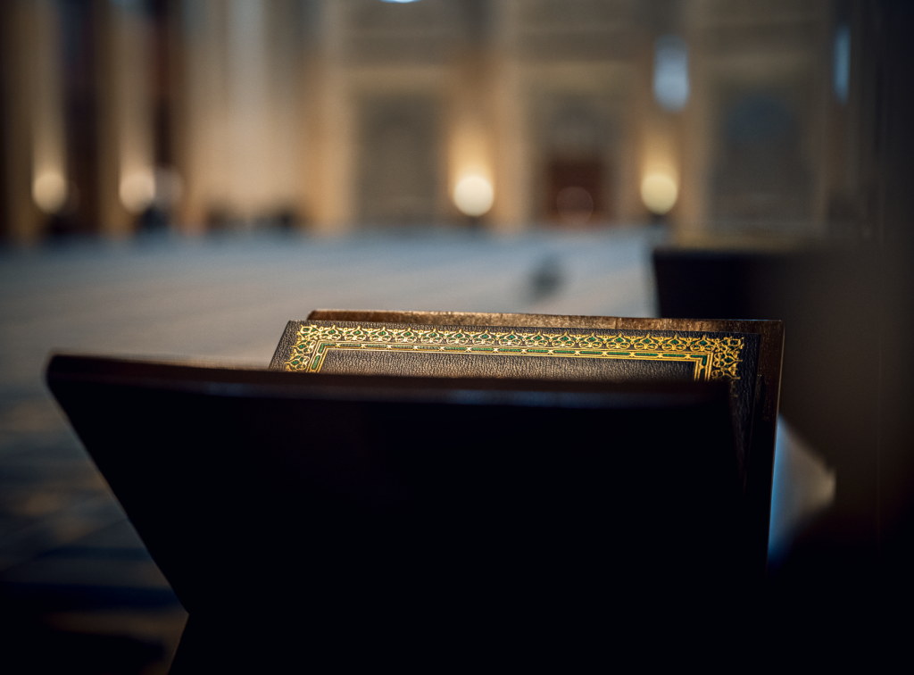 A beautifully blurred mosque interior with a Quran on a stand, creating a serene atmosphere.
