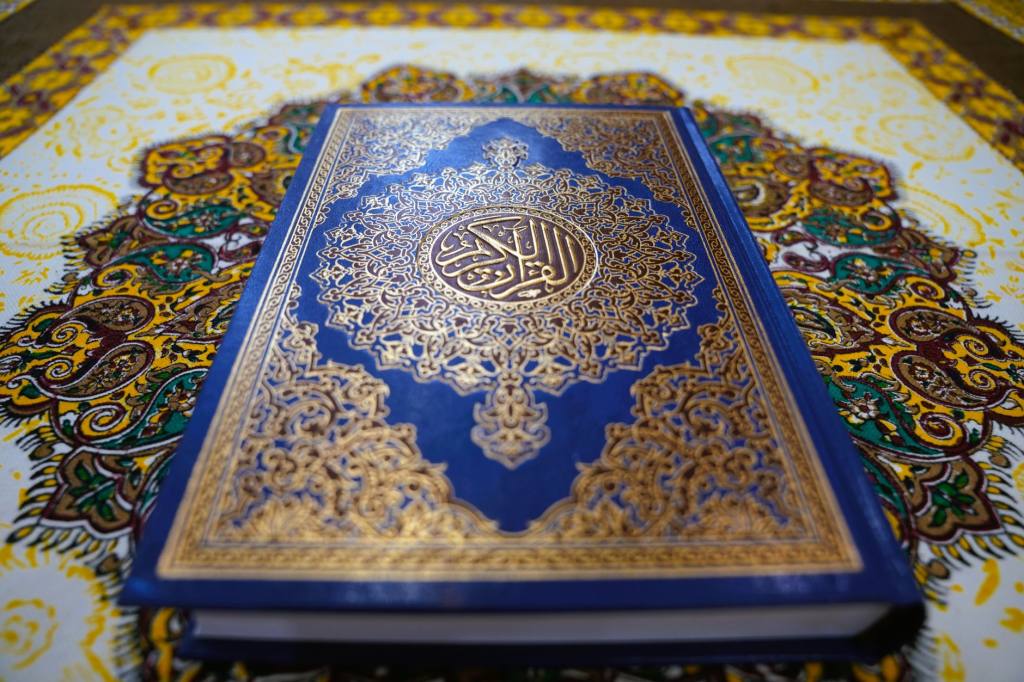 A beautifully decorated Persian Quran displayed on ornate fabric, showcasing Islamic artistry.