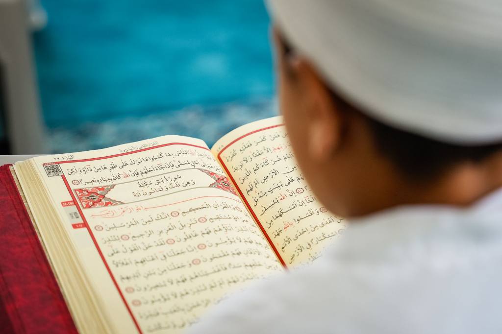 A young child immersed in reading the Quran, highlighting Islamic devotion and education.